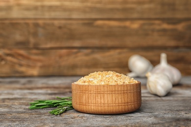 Bowl of granulated dry garlic and rosemary on wooden table