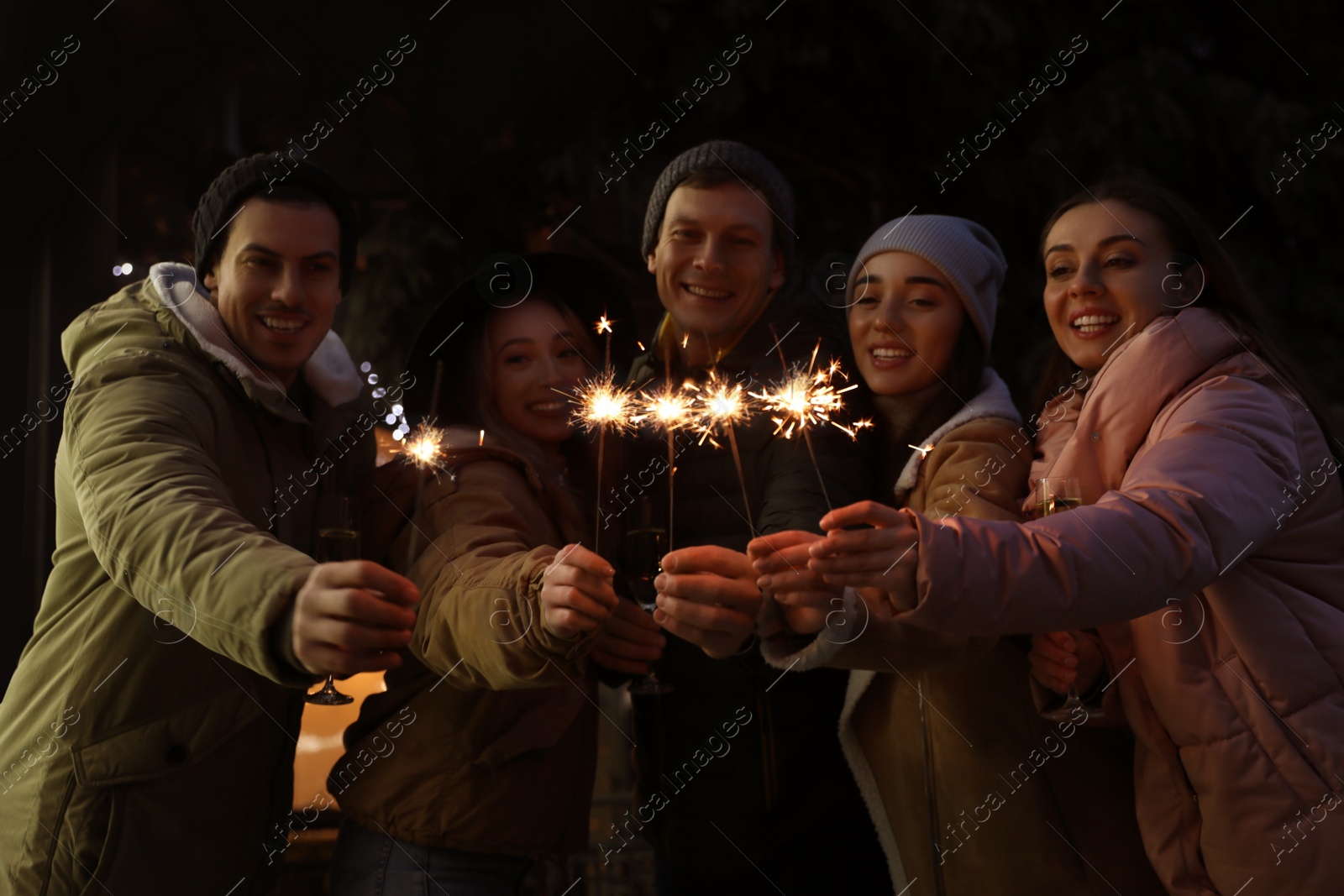 Photo of Group of happy friends with sparklers and champagne at winter fair