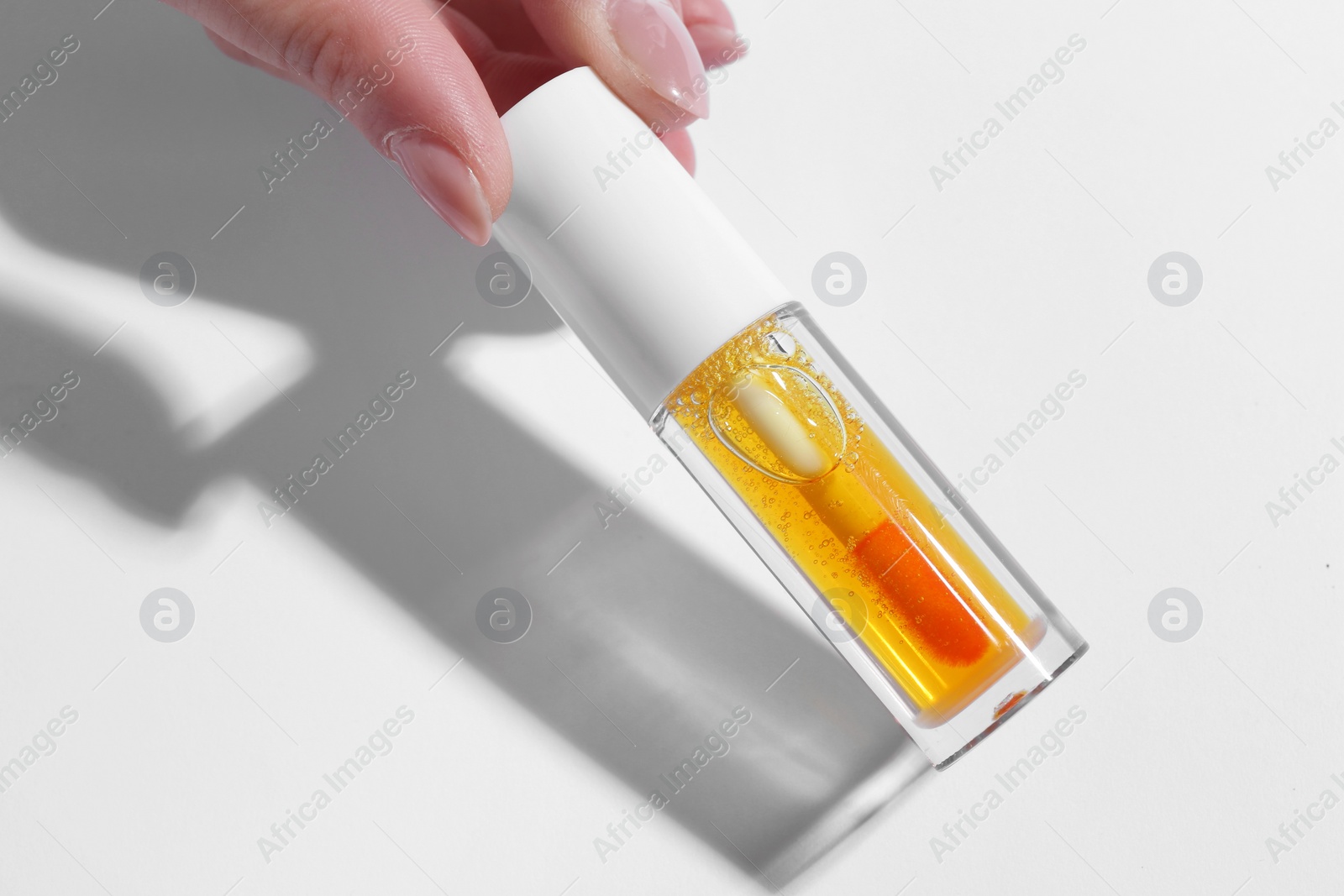 Photo of Woman with orange lip gloss on white background, closeup