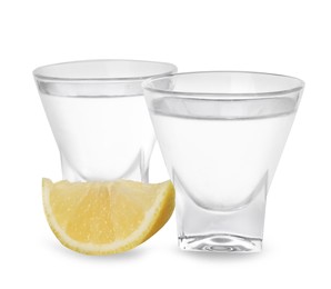 Photo of Shot glasses of vodka with lemon on white background