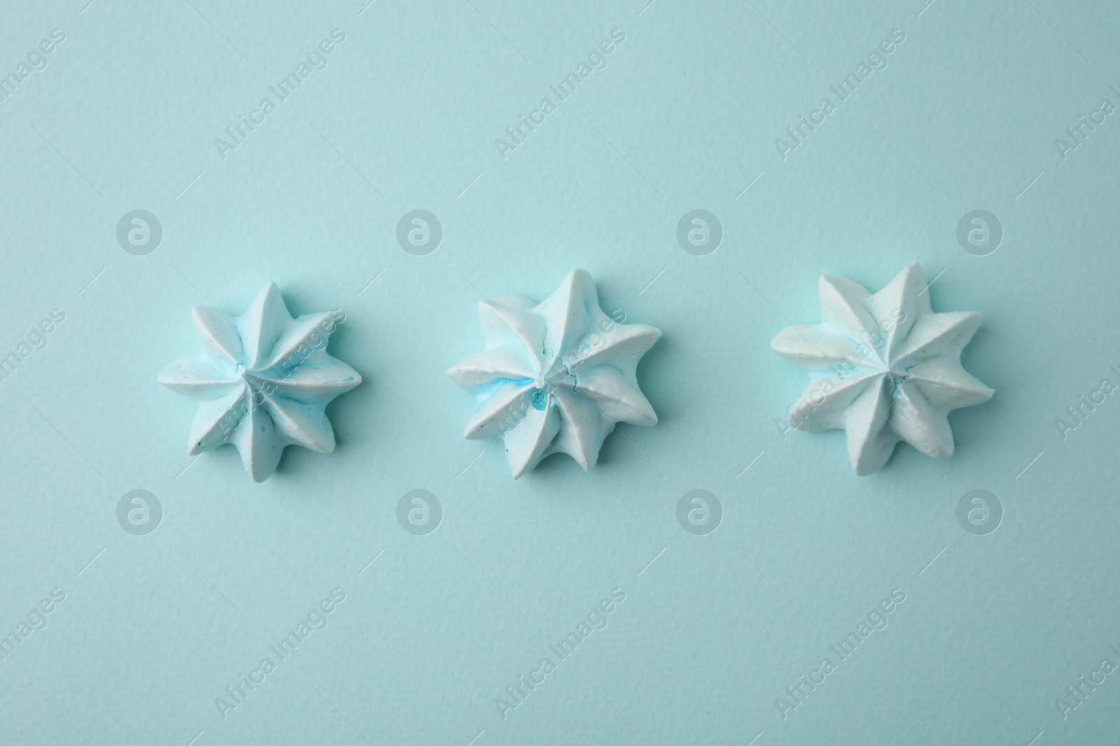 Photo of Delicious meringue cookies on light blue background, flat lay