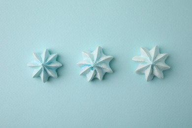 Delicious meringue cookies on light blue background, flat lay