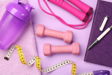 Flat lay composition with dumbbells on violet background