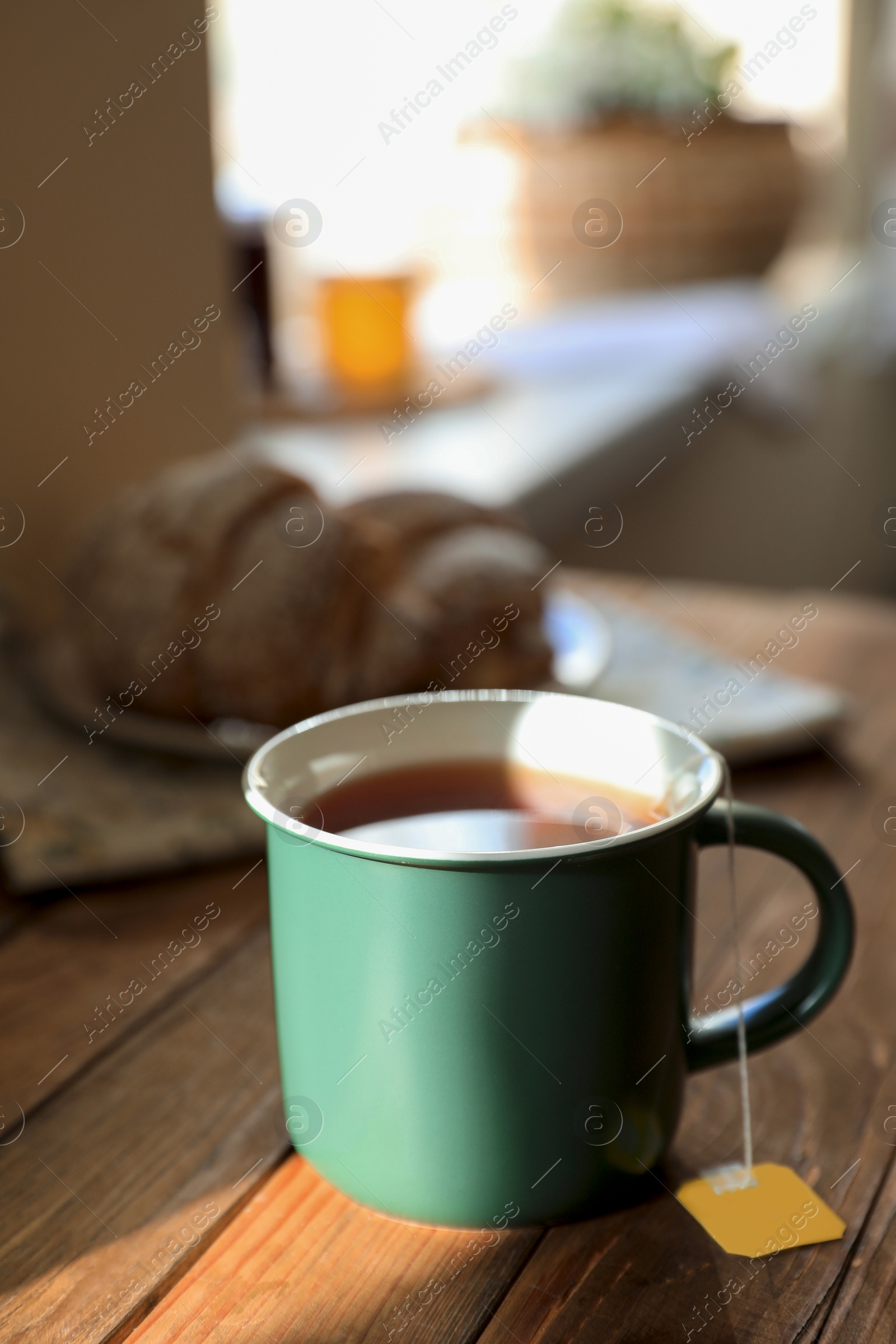 Photo of Tea bag in cup on wooden table indoors