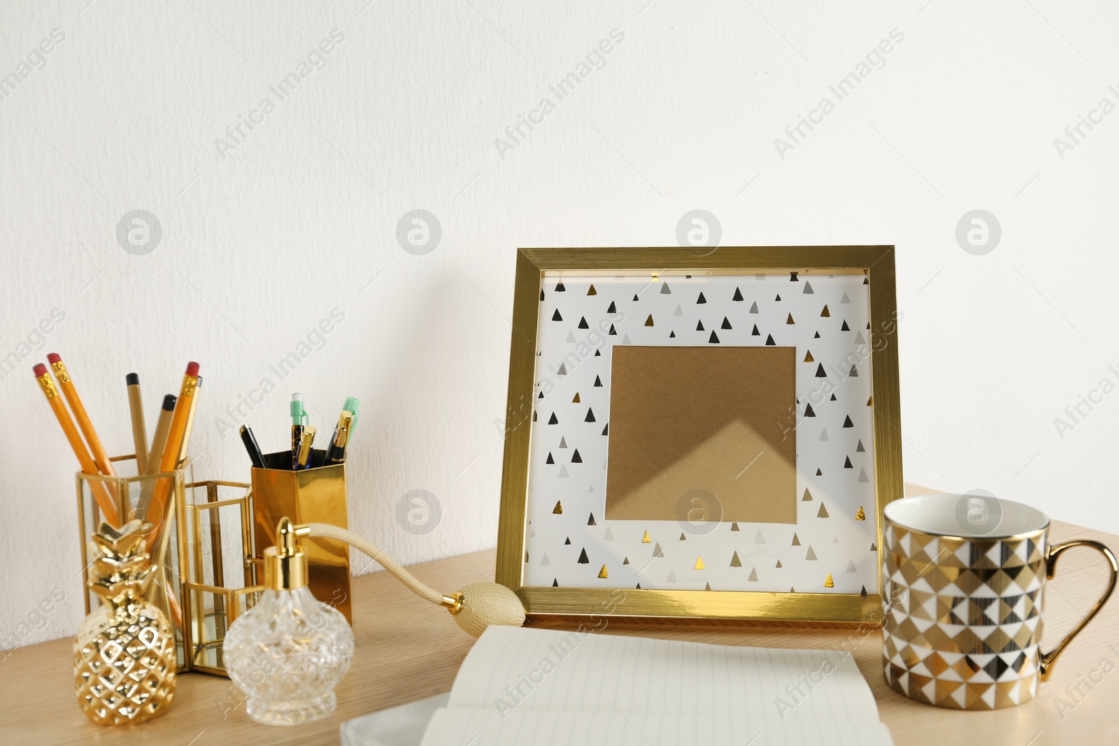 Photo of Modern workplace with notebook and golden decor on desk near wall. Stylish interior design