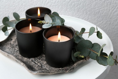 Photo of Tray with burning candles and branches on table