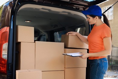Photo of Courier counting packages near delivery truck outdoors