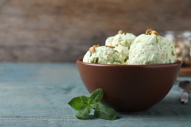 Photo of Delicious pistachio ice cream in bowl on blue wooden table. Space for text