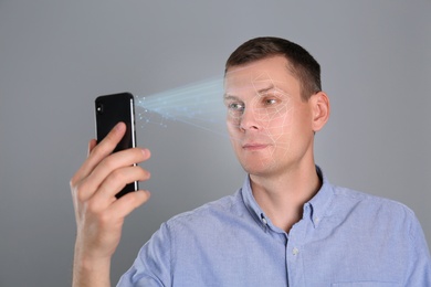 Image of Man unlocking smartphone with facial scanner on grey background. Biometric verification