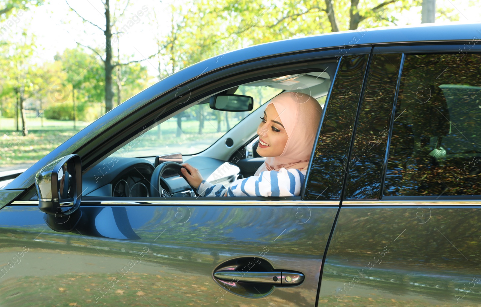 Photo of Modern Muslim woman in hijab driving car