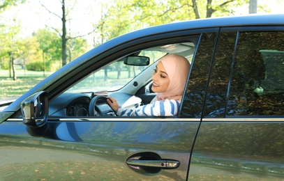 Modern Muslim woman in hijab driving car