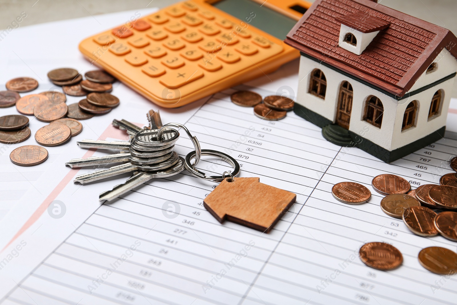 Photo of House model with calculator, keys and coins on documents, closeup. Real estate agent service