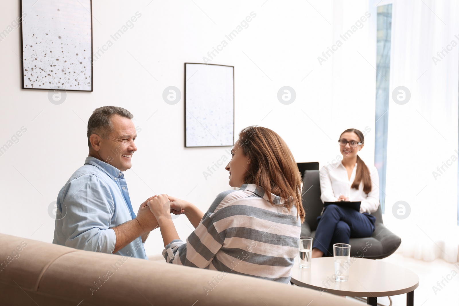 Photo of Psychotherapist and happy couple having meeting in office. Family counselling