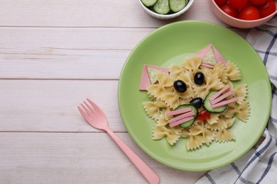Photo of Creative serving for kids. Plate with cute cat made of tasty pasta, vegetables and sausage on white wooden table, flat lay. Space for text