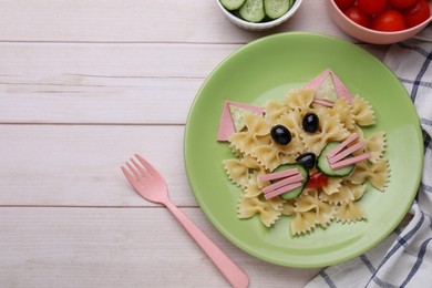 Creative serving for kids. Plate with cute cat made of tasty pasta, vegetables and sausage on white wooden table, flat lay. Space for text