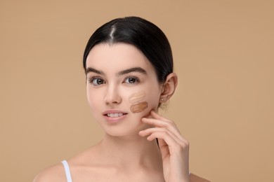 Photo of Teenage girl with swatches of foundation on face against beige background