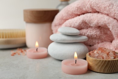 Photo of Beautiful composition with burning candles and different spa products on light grey table, closeup