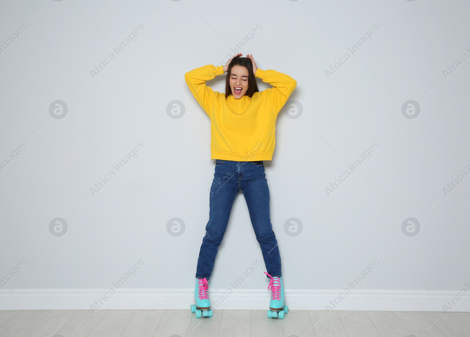 Photo of Full length portrait of young woman with roller skates near color wall