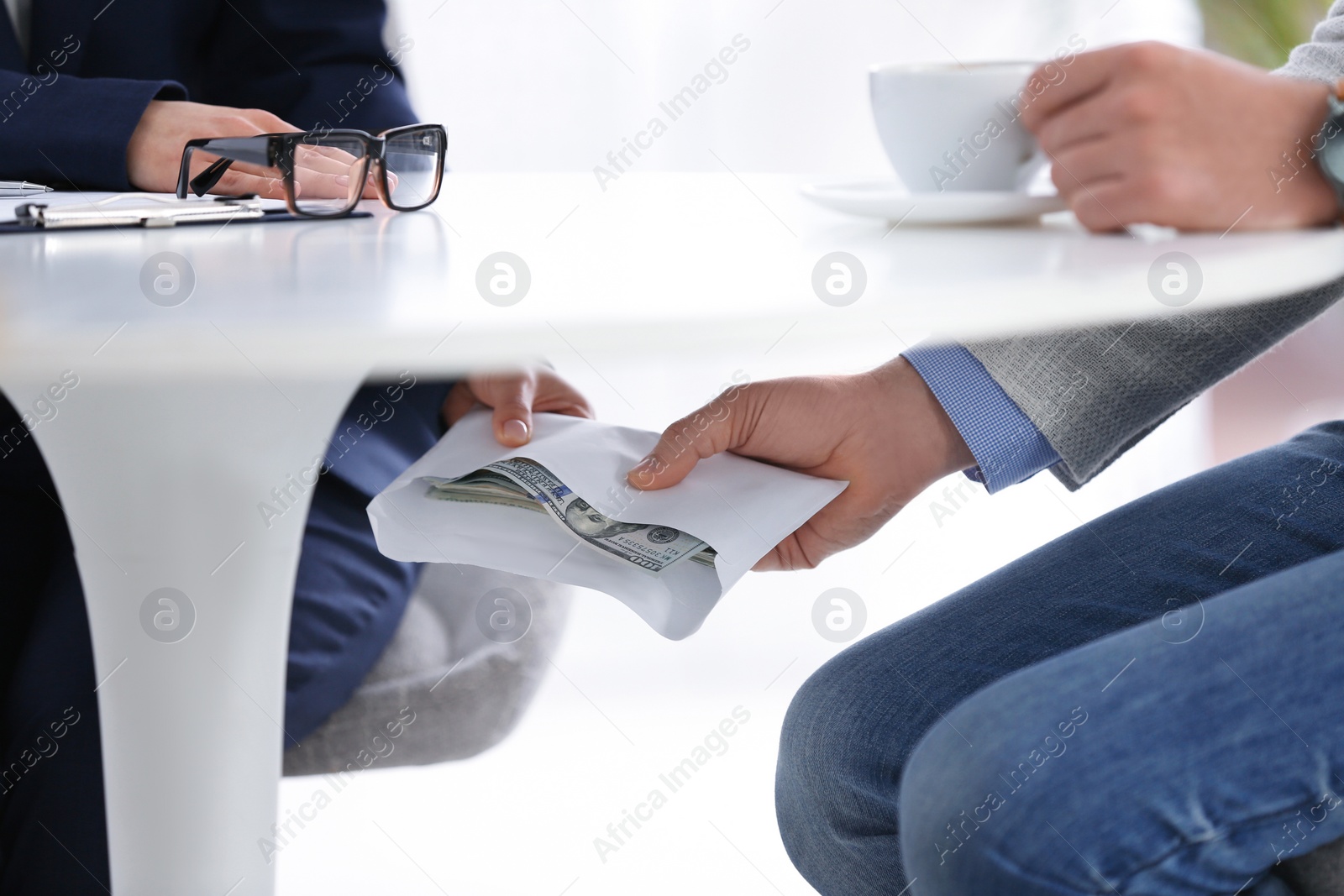 Photo of Man giving bribe to woman under table in office, closeup