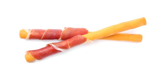 Delicious grissini sticks with prosciutto on white background, top view