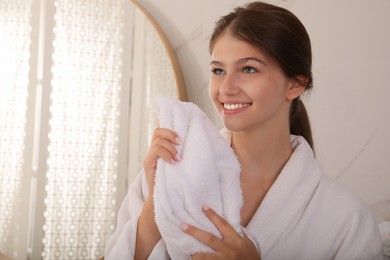 Beautiful teenage girl wiping face with towel at home