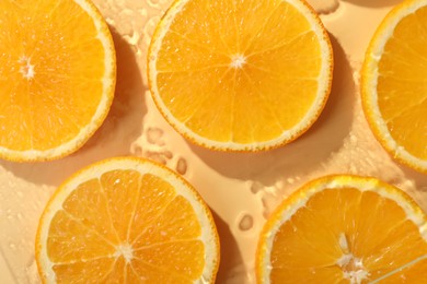 Photo of Slices of juicy orange and water on beige background, flat lay