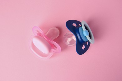 Photo of Colorful baby pacifiers on pink background, flat lay