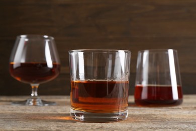Photo of Different delicious liqueurs in glasses on wooden table