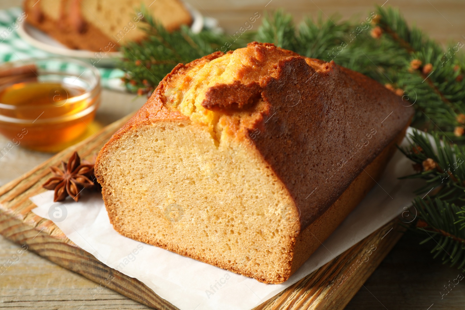 Photo of Delicious gingerbread cake and fir branch on wooden table, closeup