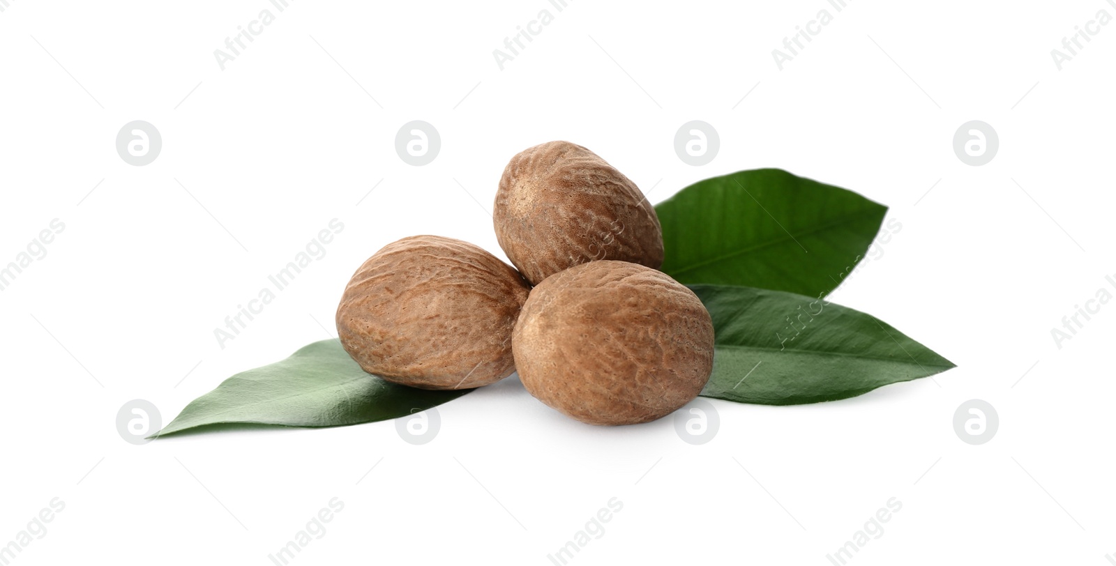 Photo of Nutmeg seeds with green leaves on white background