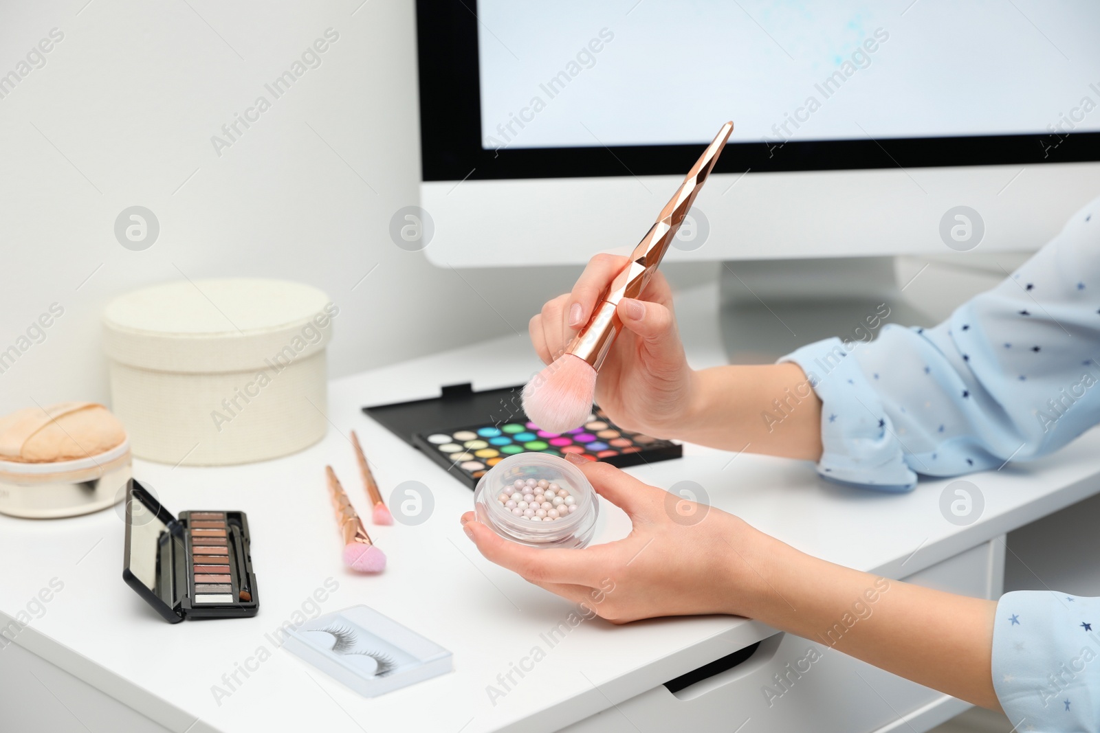 Photo of Beauty blogger with brush and highlighter at table, closeup