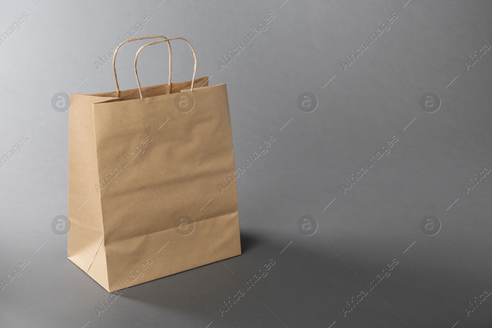 Photo of One kraft paper bag on grey background, space for text. Mockup for design