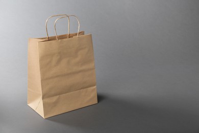 Photo of One kraft paper bag on grey background, space for text. Mockup for design