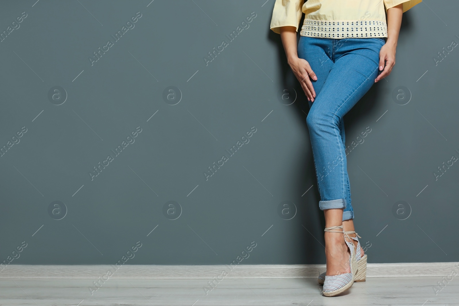Photo of Young woman with sexy legs near grey wall
