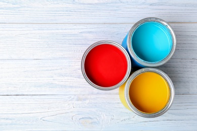 Photo of Tin cans with paint on wooden background, top view