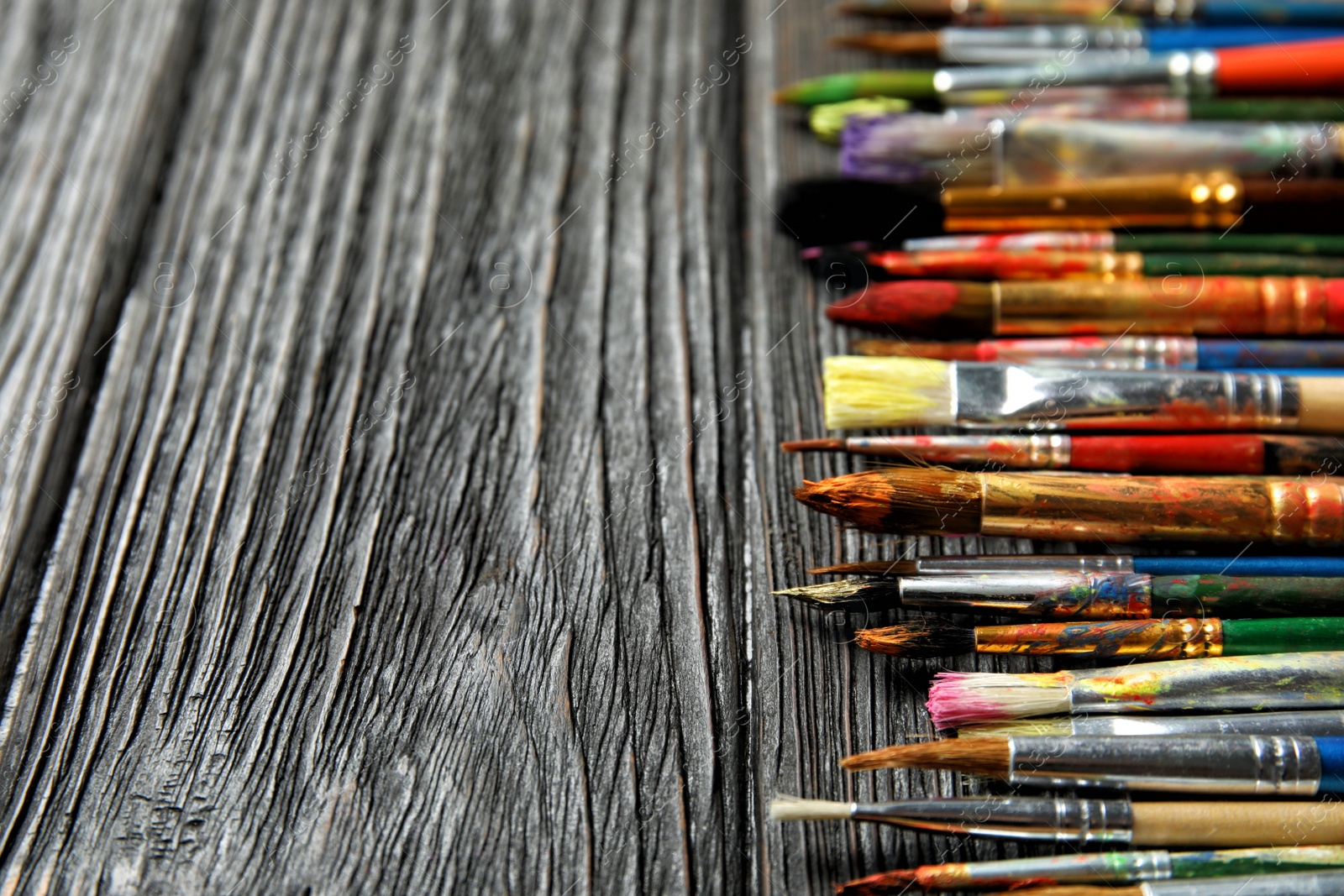 Photo of Different paint brushes on wooden table, closeup. Space for text