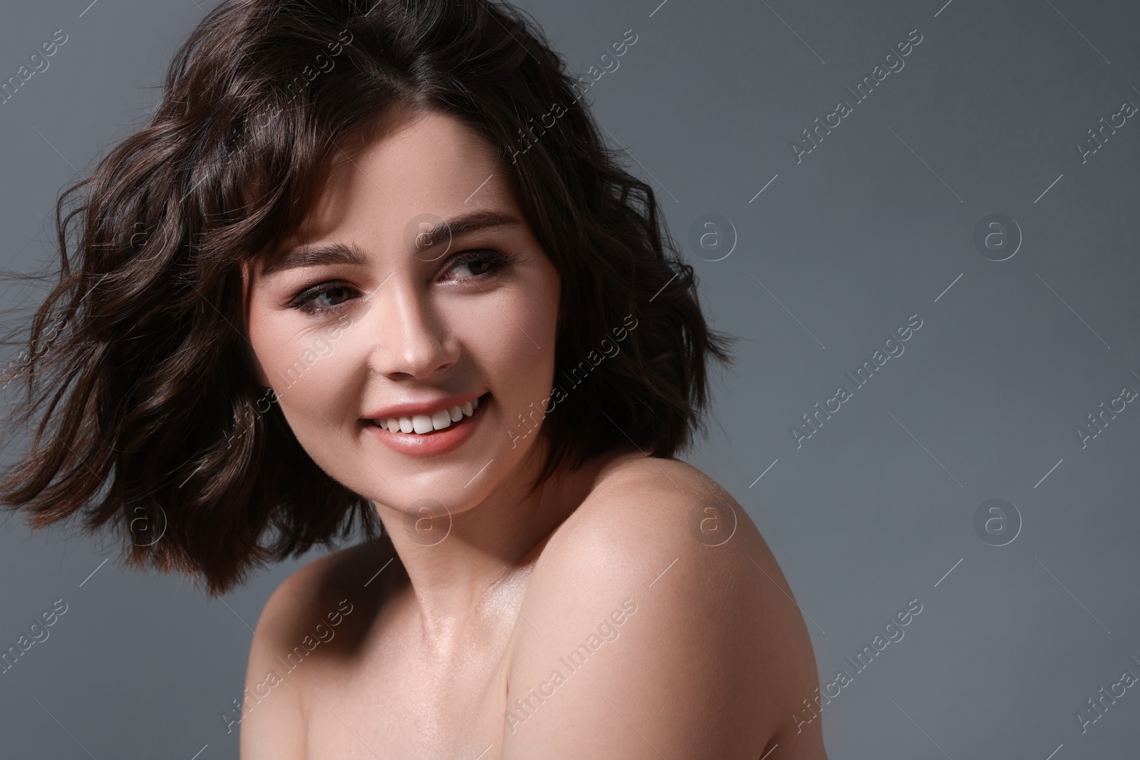 Photo of Portrait of beautiful young woman with wavy hairstyle on grey background. Space for text