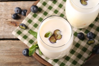 Photo of Composition with tasty yogurt in glasses and blueberries on wooden table, top view