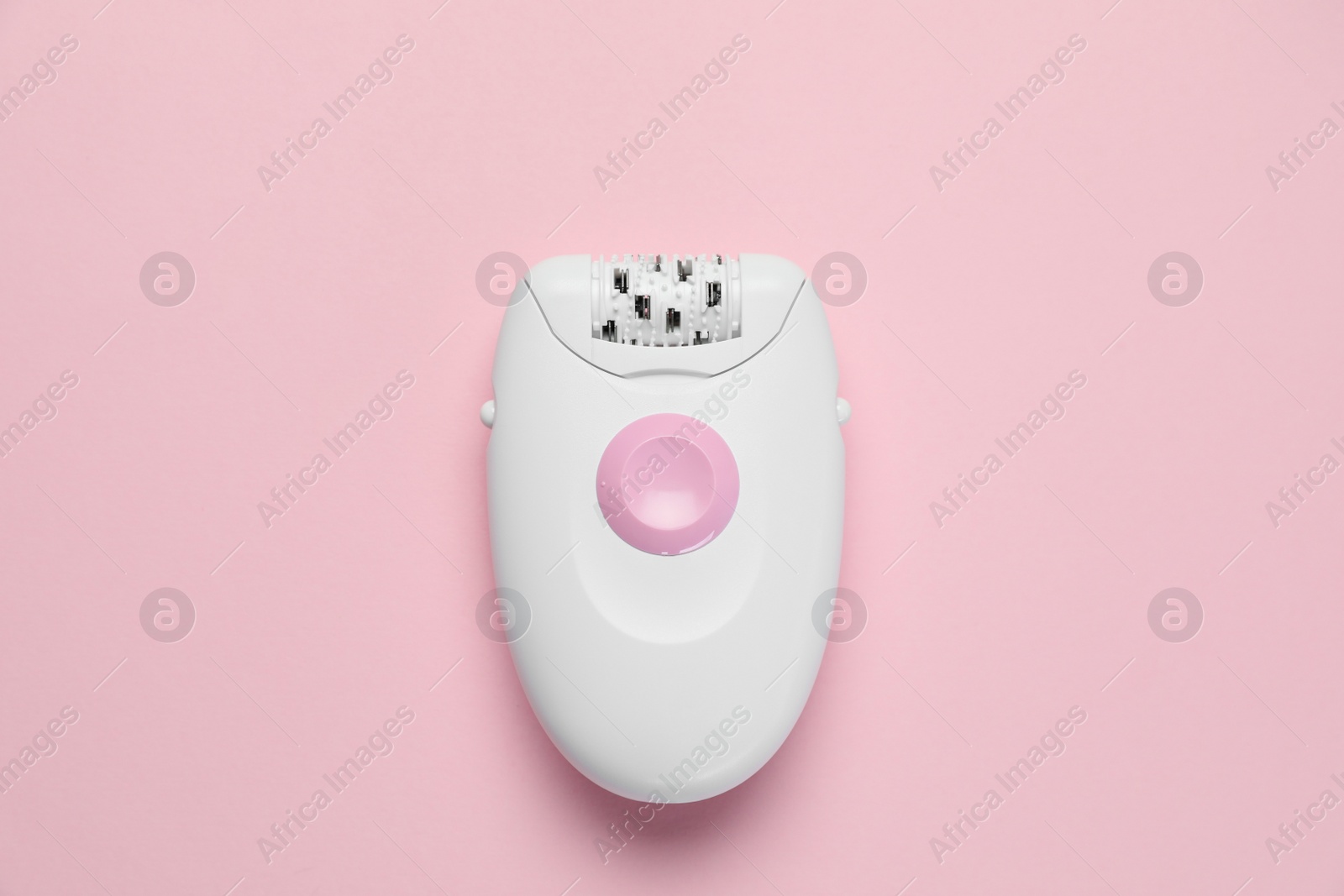 Photo of Modern epilator on pink background, top view