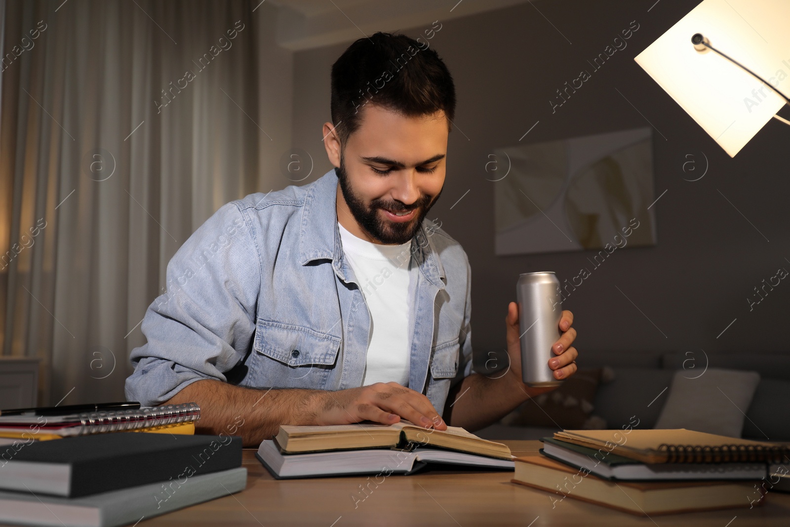 Photo of Young man with energy drink studying at home