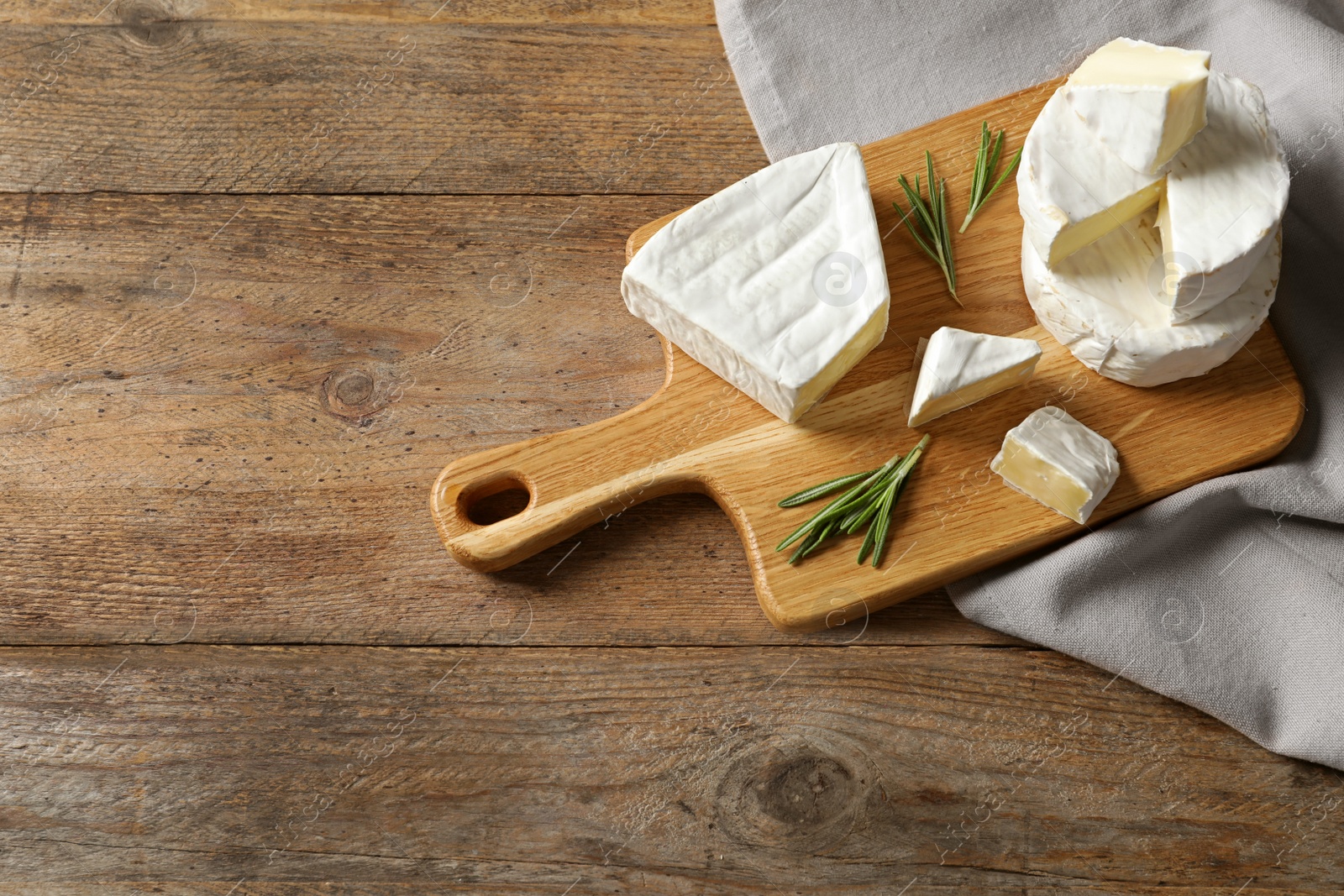 Photo of Wooden board with delicious cheeses on table, above view. Space for text