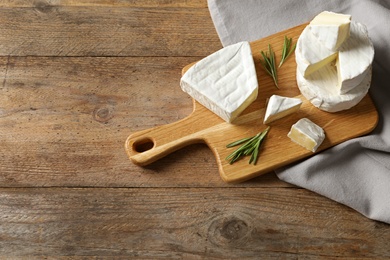 Photo of Wooden board with delicious cheeses on table, above view. Space for text