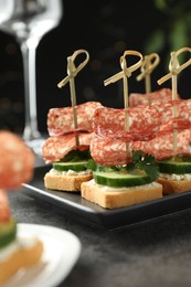 Photo of Tasty canapes with salami, cucumber and cream cheese on grey table