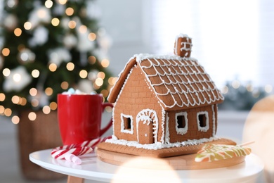 Photo of Beautiful gingerbread house decorated with icing on white table indoors