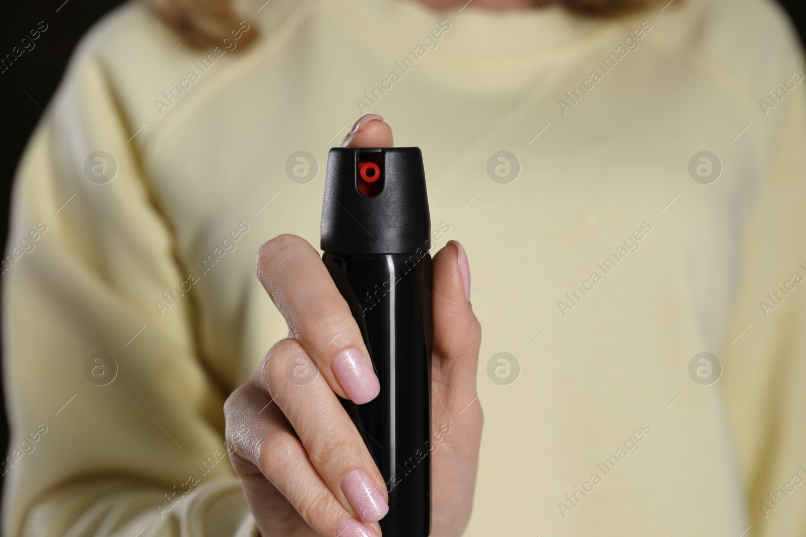 Photo of Young woman using pepper spray, closeup. Space for text