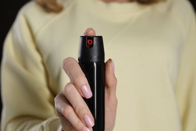 Young woman using pepper spray, closeup. Space for text