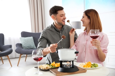 Happy couple enjoying fondue dinner at home