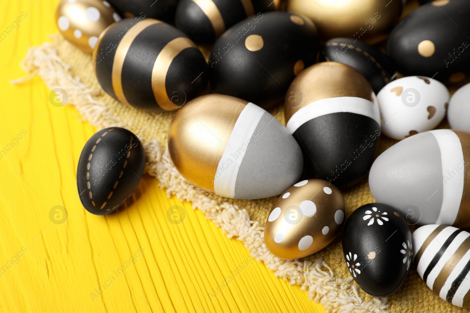 Photo of Many beautifully decorated Easter eggs on yellow wooden table, closeup