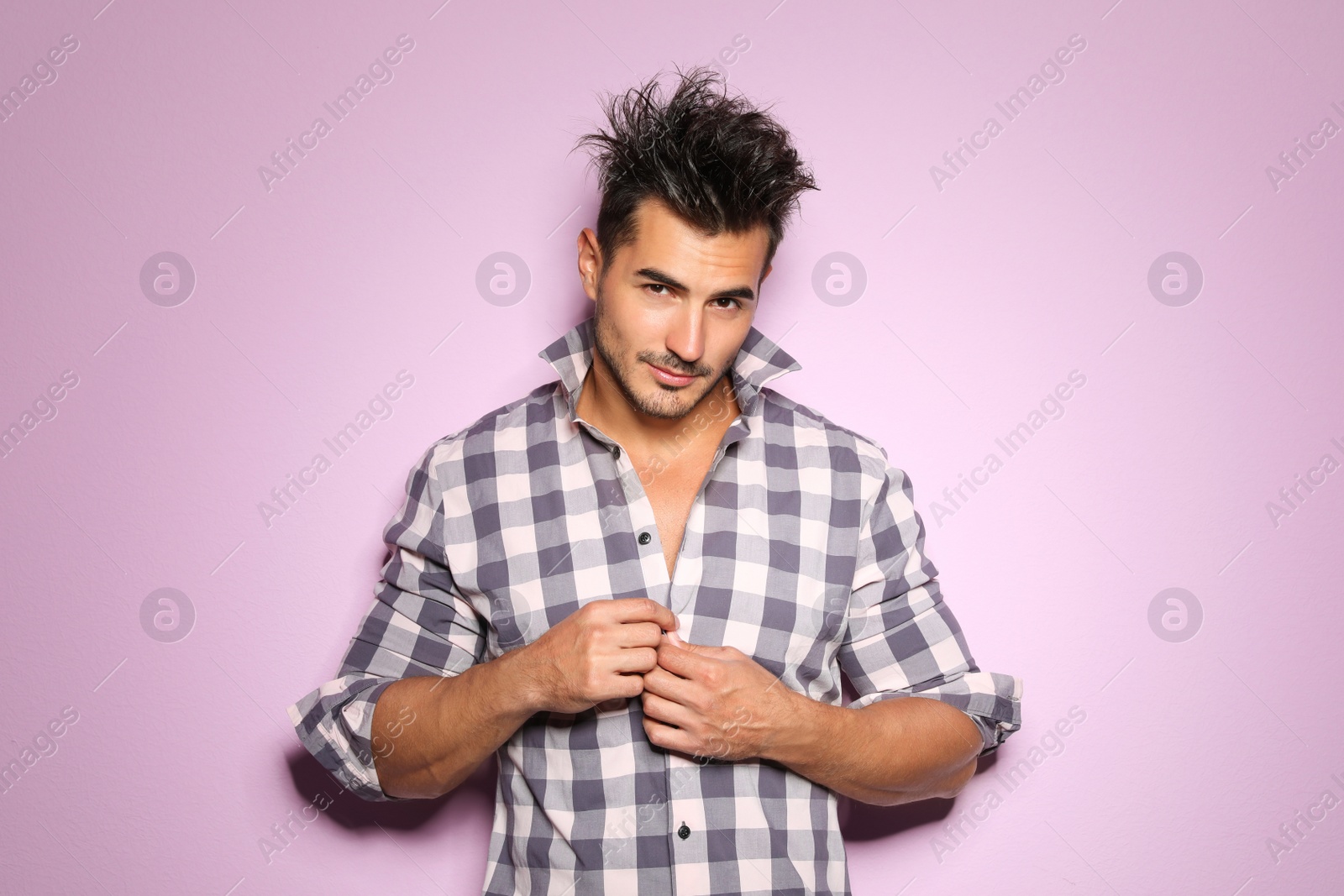 Photo of Young man with trendy hairstyle posing on color background