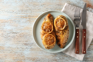 Photo of Delicious lemon chicken served on wooden table, flat lay